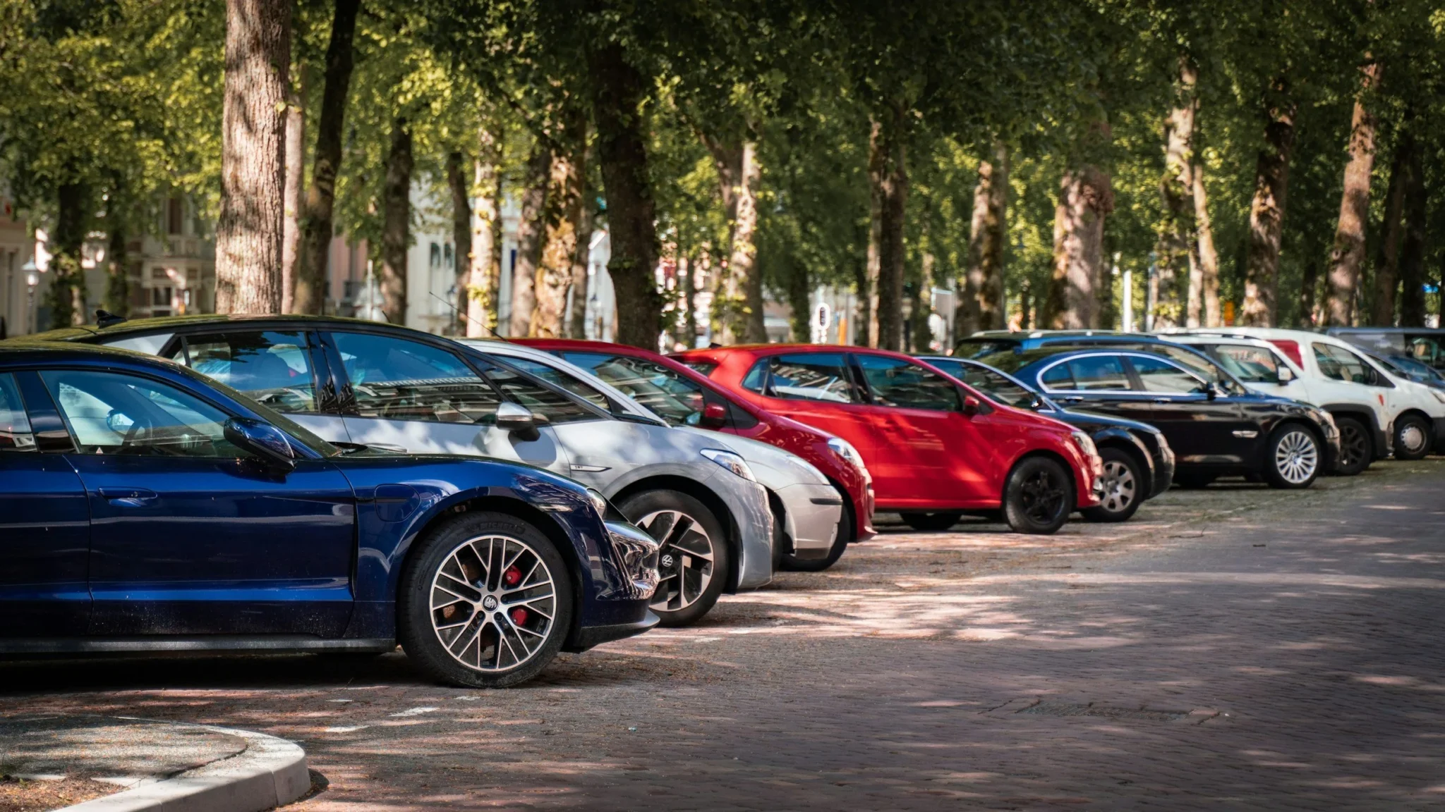 A row of cars parked along a tree-lined street, representing an automotive industry digital marketing project